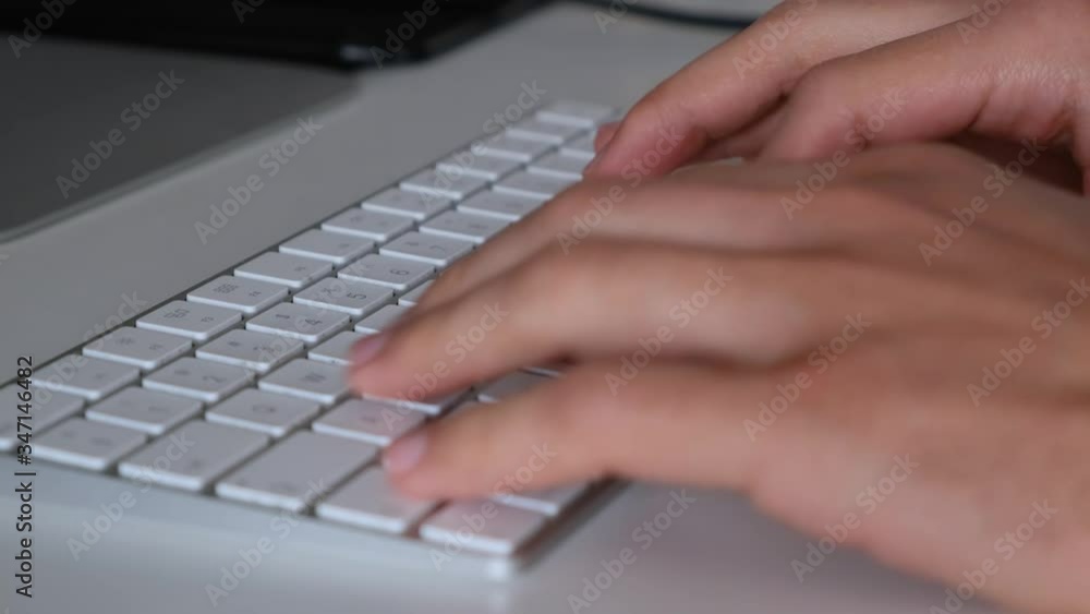 Super close up shot of hands typing on a white keyboard. Office worker working from home on a computer with a thin keyboard, bluetooth mouse on modern clean minimalist table, fast key typing, clicking Super close up shot of hands typing on a white keyboard. Office worker working from home on a computer with a thin keyboard, bluetooth mouse on modern clean minimalist table, fast key typing, clicking