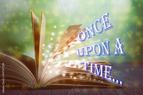 Open book of fairy tales with magic light and text Once upon a time
