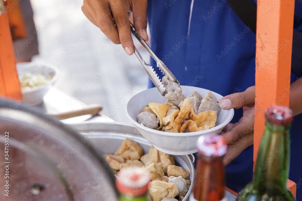 indonesian meatball street food vendor preparing the dish using tongs