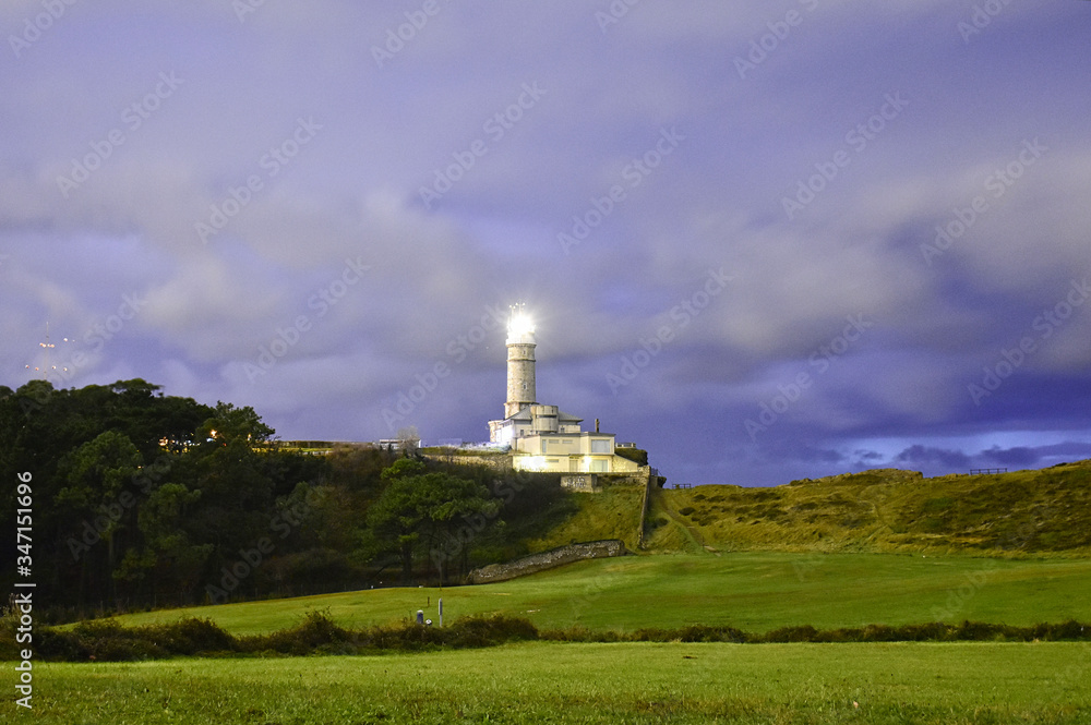 lighthouse illuminated at dusk over blue sky