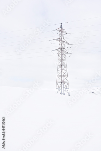 snowy landscape with electric tower and old fences