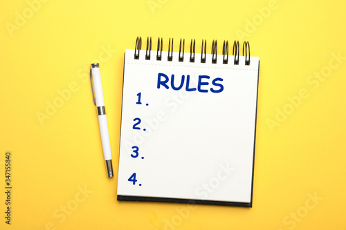 Notebook with list of rules and pen on yellow background, flat lay photo