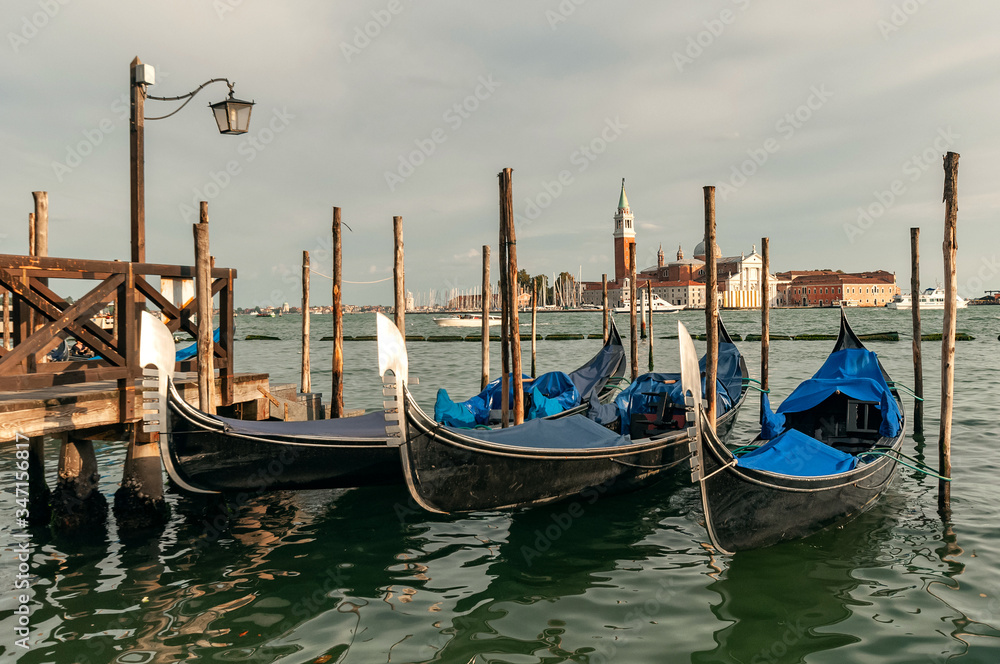 Traditional venetian gondolas floating on the water in lagoon on San Giorgio island background