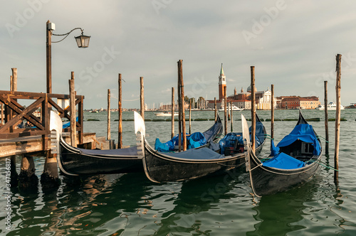 Traditional venetian gondolas floating on the water in lagoon on San Giorgio island background © Gioia