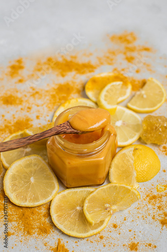 Flower honey in a jar, lemons and turmeric on a light background. Alternative medicine concept. Super food.