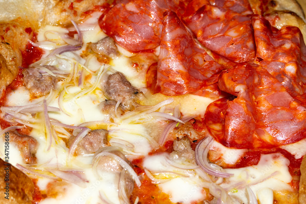 closeup of soft pizza topped with tomato mozzarella salami sausage onion closeup of soft pizza topped with tomato mozzarella salami sausage onion
