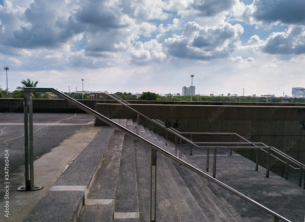 Stairs and railing entrance of stadium in shade under cloudy sky
