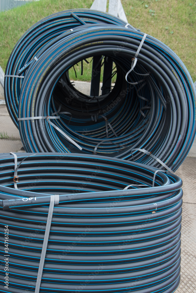 a lot of rolled plastic pipes. stock, preparation for laying. Rolls of black pipes in the open. a lot of rolled plastic pipes. stock, preparation for laying. Rolls of black pipes in the open.