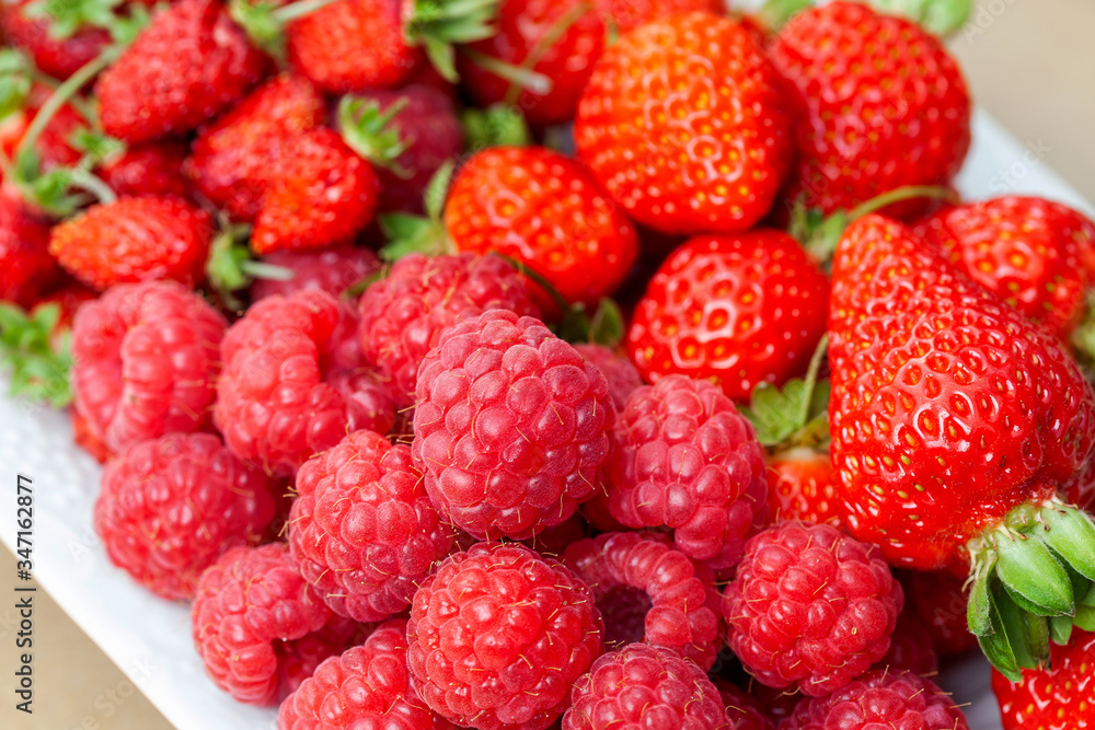 Ripe raspberries, strawberries and wild strawberries on a plate Ripe raspberries, strawberries and wild strawberries on a plate