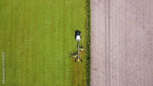 Traktor mit Heuwender bringt nach Mahd der  Wiese Grasschnitt für Grassilage in Reihe, Landwirtschaft aus der Vogelperspektive photo