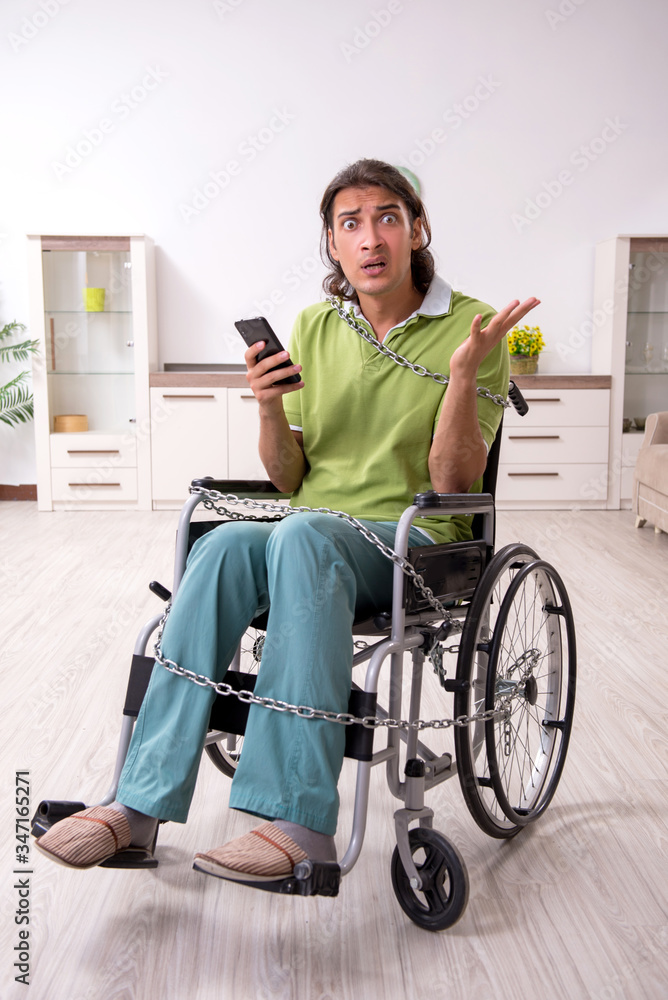 Young male invalid in wheel-chair suffering at home Young male invalid in wheel-chair suffering at home