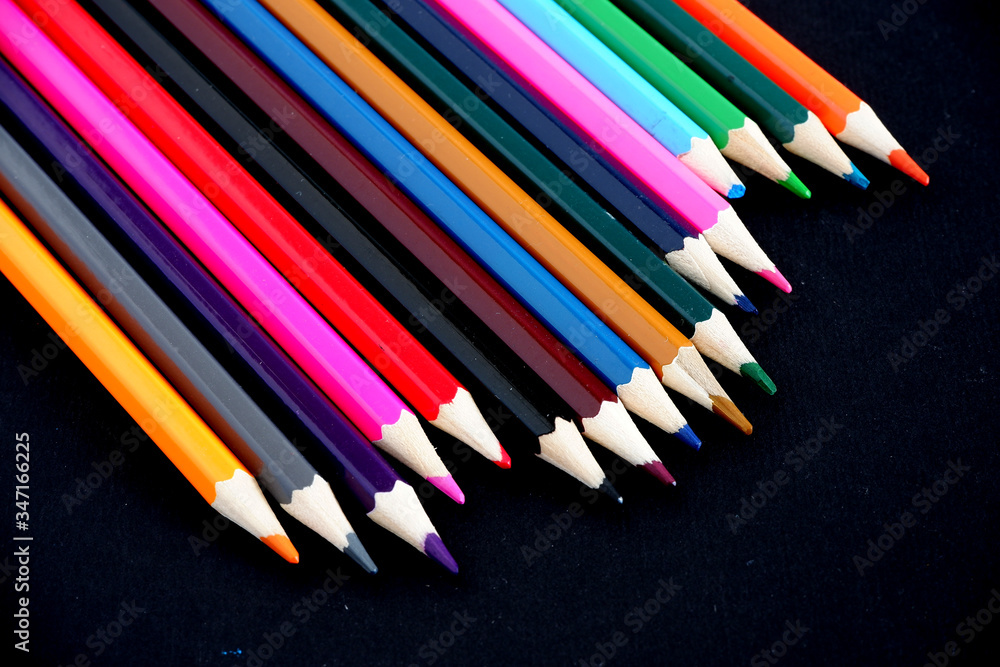 Colored pencils on a black textured background. Suitable for advertising background. Suitable for mockups Colored pencils on a black textured background. Suitable for advertising background. Suitable for mockups
