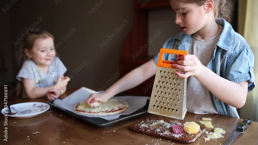children prepare pizza at home. fun activity with kids. child cook food on kitchen. girl rubs cheese on a grater children prepare pizza at home. fun activity with kids. child cook food on kitchen. girl rubs cheese on a grater