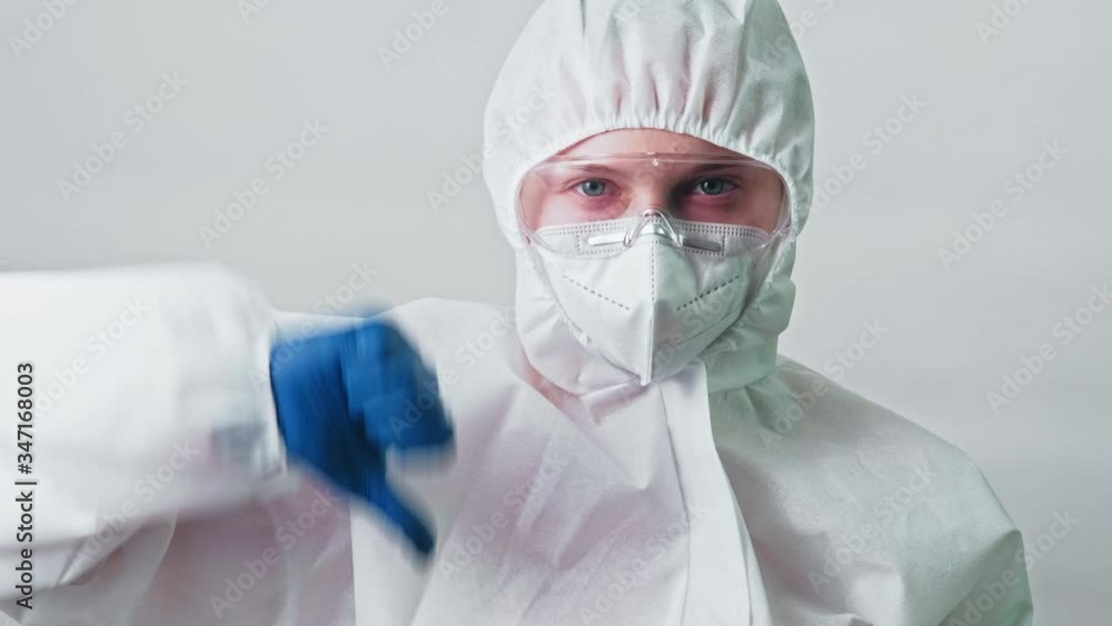 Medical scientist. Coronavirus pandemic. Female lab technician in white ppe googles mask showing thumb down. Medical scientist. Coronavirus pandemic. Female lab technician in white ppe googles mask showing thumb down.