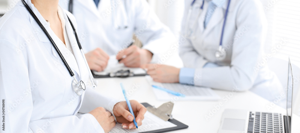 Group of unknown doctors discussing problems to stop coronavirus pandemic while sitting at meeting in clinic, close-up . Medicine concept Group of unknown doctors discussing problems to stop coronavirus pandemic while sitting at meeting in clinic, close-up . Medicine concept