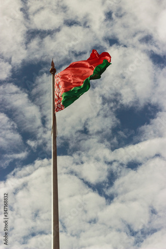 the flag of the Republic of Belarus develops in the wind in the clouds of the sky