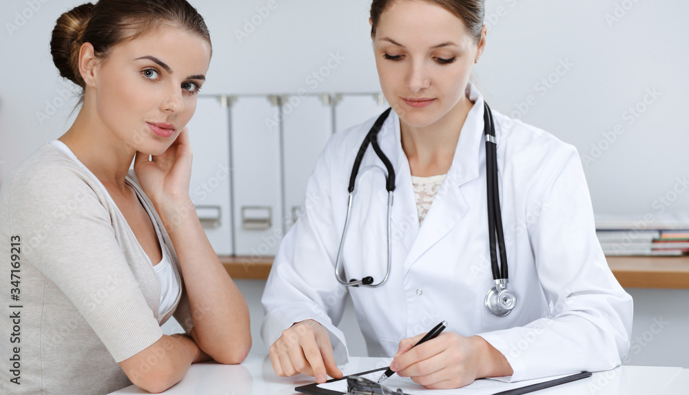 Doctor and patient are sitting and discussing health examination results in clinic office. Health care, medicine and good news concepts Doctor and patient are sitting and discussing health examination results in clinic office. Health care, medicine and good news concepts