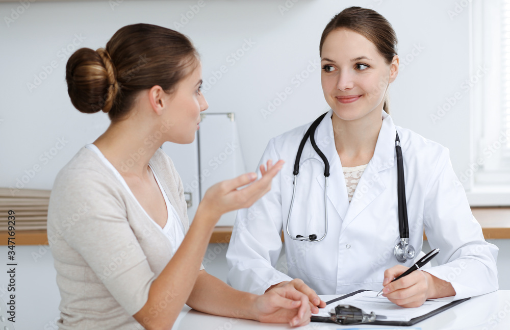 Doctor and patient are sitting and discussing health examination results in clinic office. Health care, medicine and good news concepts Doctor and patient are sitting and discussing health examination results in clinic office. Health care, medicine and good news concepts