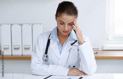 Woman-doctor sitting and working at clinic office. Portrait of female physician. Medicine concept © rogerphoto