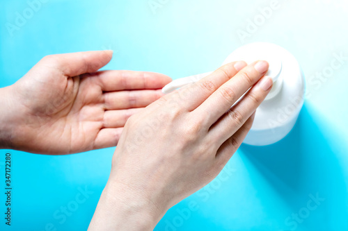 女性の手と消毒用ボトルとコピースペースと水色背景 女性が手を消毒するところ