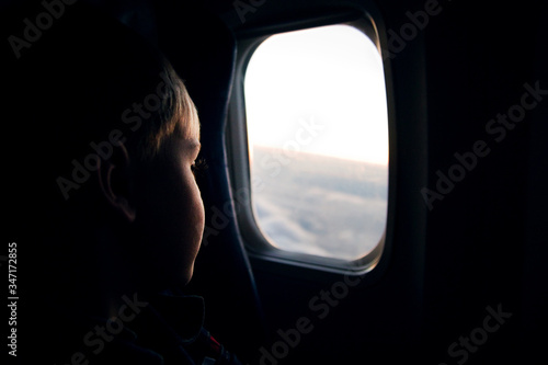 Silhouette of a face of child kid boy on the background of an airplane window in flight