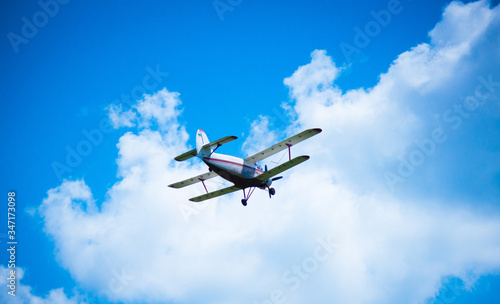 Biplane airplane flies in a picturesque cloudy sky. Old school aircraft aviation