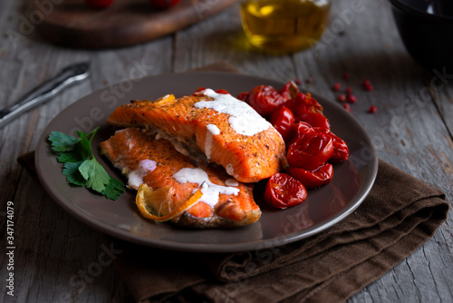 Cooked salmon fish with cherry tomatoes on dark background