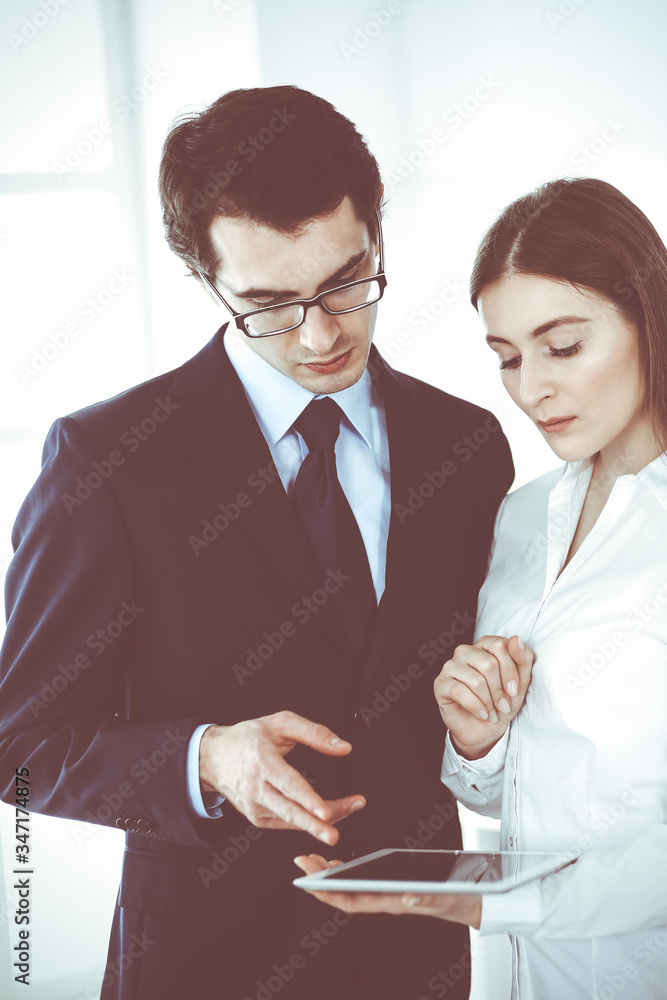 Businessmen and woman using tablet computer in modern office. Colleagues or company managers at workplace. Partners discussing contract. Business concept Businessmen and woman using tablet computer in modern office. Colleagues or company managers at workplace. Partners discussing contract. Business concept