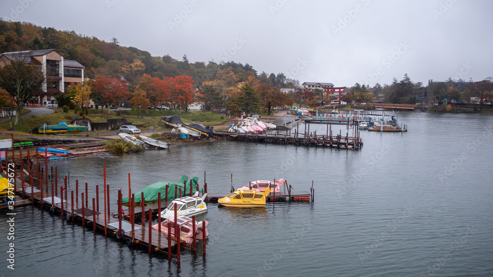Beautiful view of colorful autumn tree in small town looking from ferry boat on lake with cloudy sky for background with copy space, Nikko