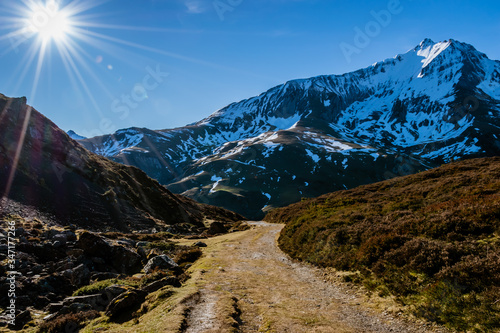 A picturesque landscape view of a wide hiking trail leading to the snow capped French Pyrenees mountain range early in the morning in winter (Col de Soum)