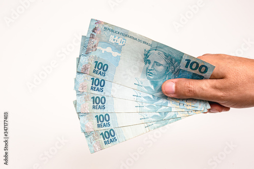 100 reais bills from Brazil, held by male hand on isolated white background. Banknotes of one hundred reais from brazil, payday. photo