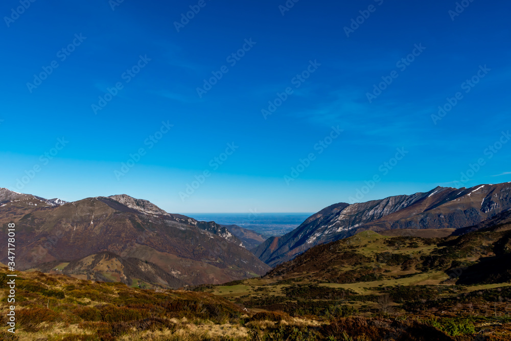 A picturesque landscape view of the snow capped French Pyrenees mountain range with the plain horizon visible in the distance early in the morning in winter (Col de Soum)