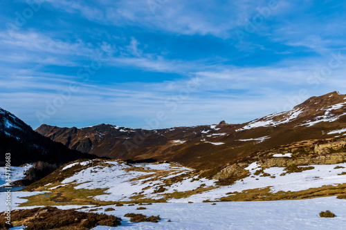 A picturesque landscape view of the snow covered French Pyrenees mountain range in the afternoon under the bright blue sky in winter