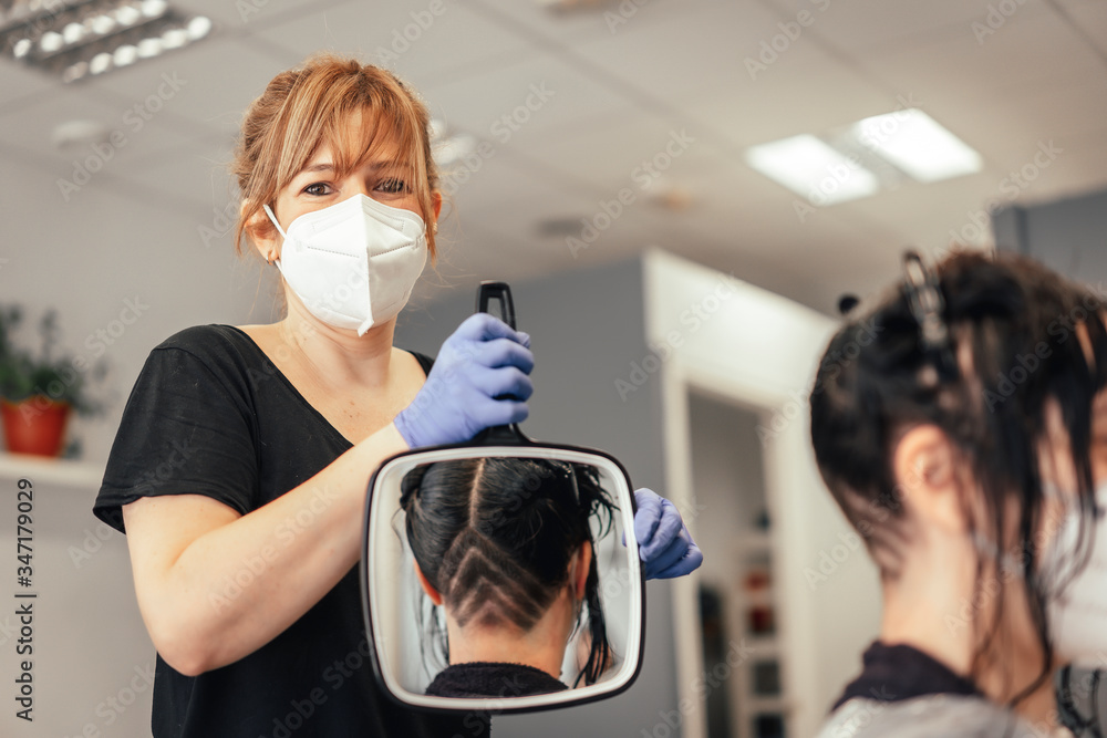 Hairdresser with a mask showing the client the haircut in a mirror