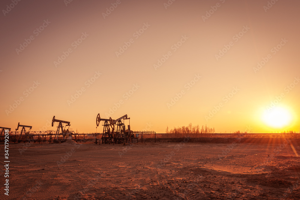 Obraz premium Oil pump rig. Oil and gas production. Oilfield site. Pump Jack are running. Drilling derricks for fossil fuels output and crude oil production. War on oil prices. Global coronavirus COVID 19 crisis.