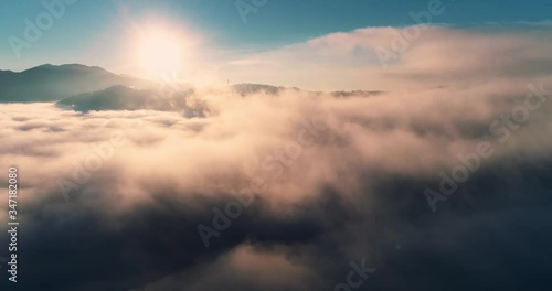 Aerial view flying through cumulus thunderclouds at sunrise. Gold colored sunset cloudiness in high contrast. Real sky. The concept of dreams and weather forecast. Сamera moves forward