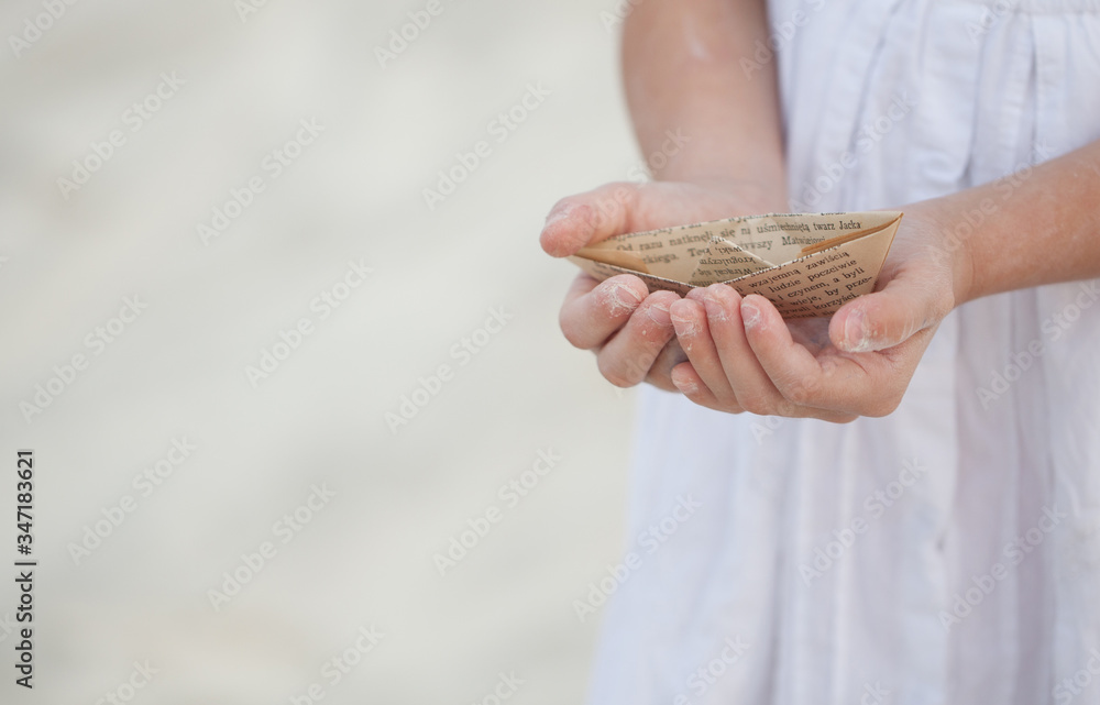 a child holding a paper boat in his hands