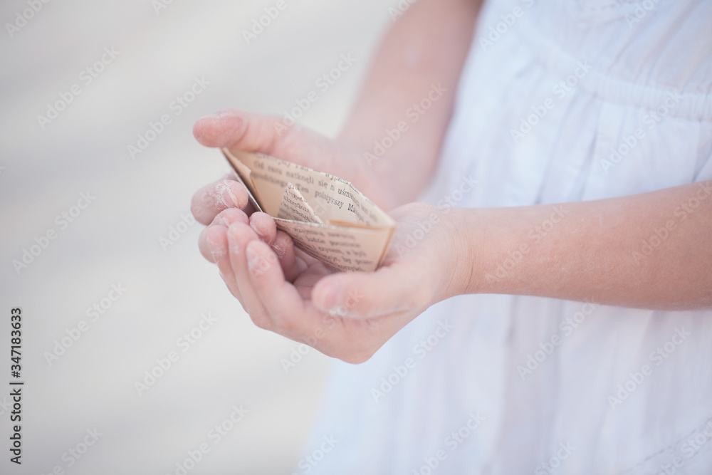 a child holding a paper boat in his hands