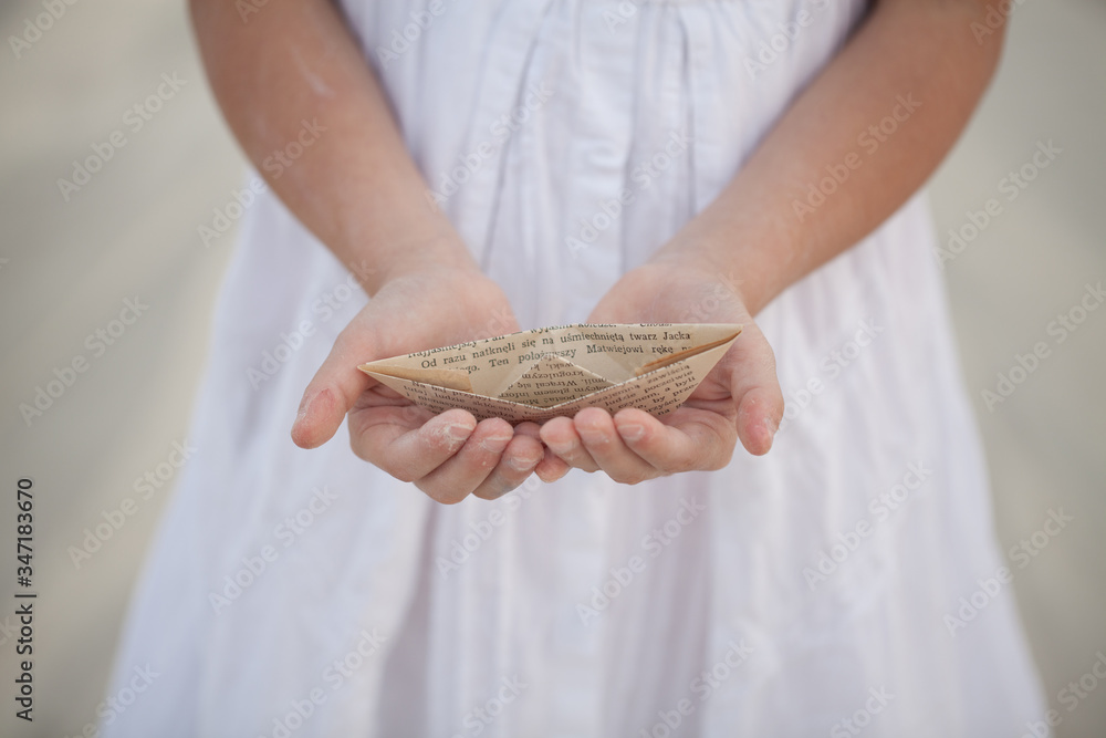 a child holding a paper boat in his hands