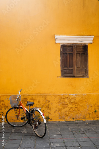 An old Bicycle against a yellow wall with a wooden window in the old city of Hoi an. Place for the label.Vietnam. © tatiana1987