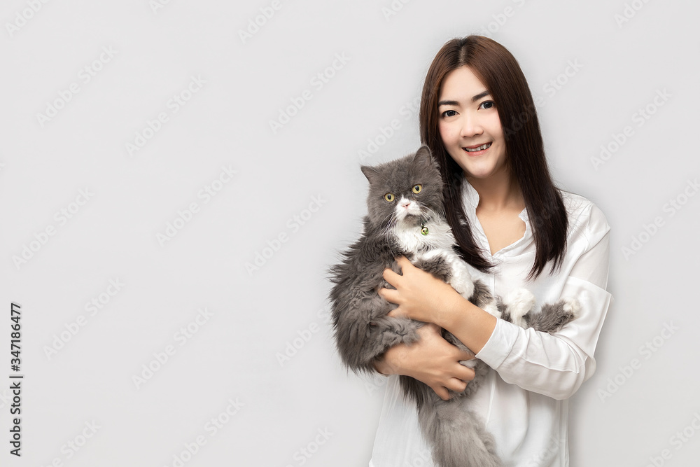 Asian woman with long hair wearing a white shirt is carrying a grey Persia Cat. Asian woman with long hair wearing a white shirt is carrying a grey Persia Cat.