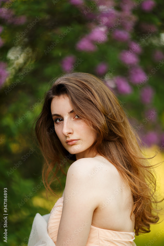 Romantic portrait of young beautiful girl standing in spring lilac garden Romantic portrait of young beautiful girl standing in spring lilac garden