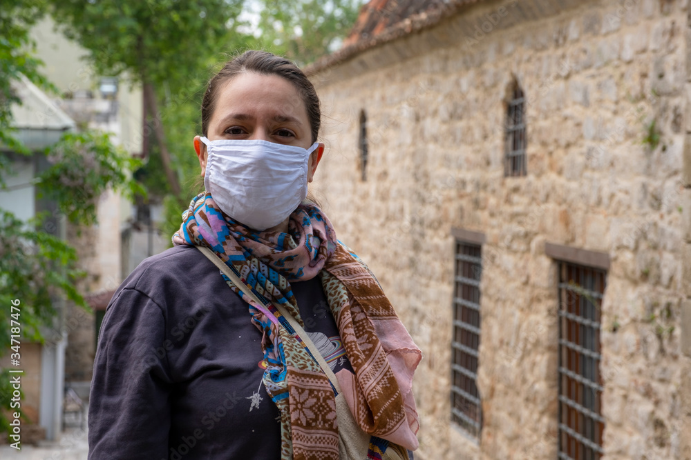 Young adult woman standing look at the camera with mask during corona (covid19) outbreak in the street. Young adult woman standing look at the camera with mask during corona (covid19) outbreak in the street.