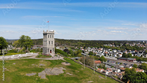 Created by dji drone camera of Slottsfjell an architecture building from medieval times in the oldest city of Norway with a village in the background and the Norwegian flag on top in the summer photo
