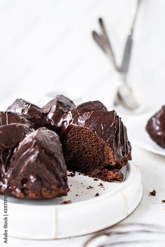 Homemade Chocolate bundt cake with melted chocolate on white background.Close up view, selective focus