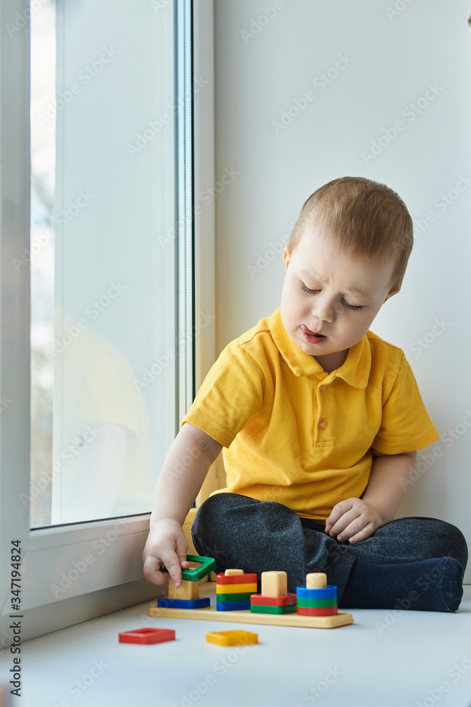 Small baby boy is sitting on windowsill, playing an educational game. Small baby boy is sitting on windowsill, playing an educational game.