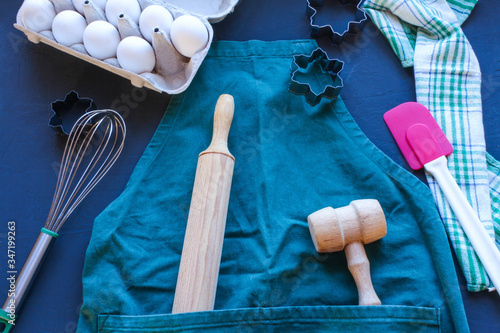 Baking utensils and ingredients are spread out on the dark surface.