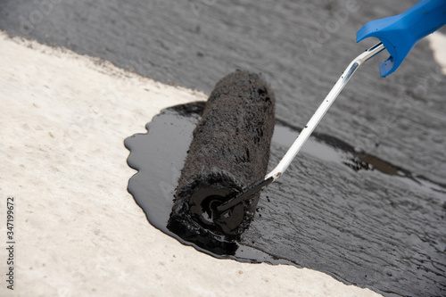 Photography Worker applies bitumen mastic on the foundation