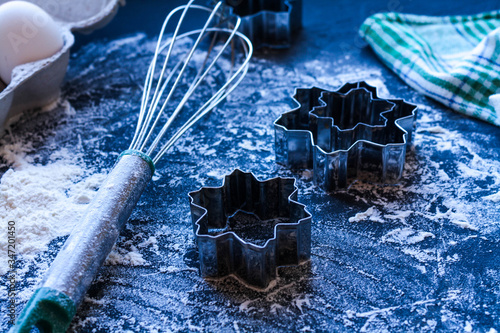 Baking utensils and ingredients are spread out on the dark surface.