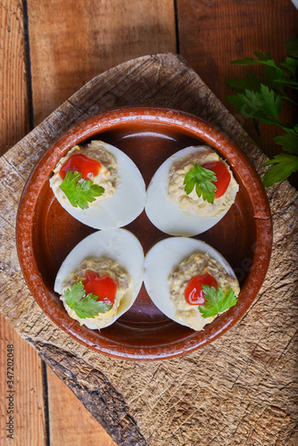 stuffed eggs on a rustic ground plate and surrounded by ingredients